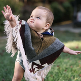 baby standing with the arms out wearing a fall color poncho