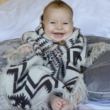 baby smiling wearing a brown and white poncho 