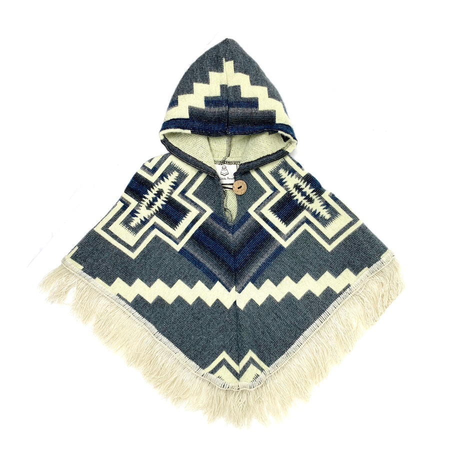 front of baby poncho in a denim like blue with white crosses on each side and a white zigzag line across horizontally. the hood is blue with a white triangle shape